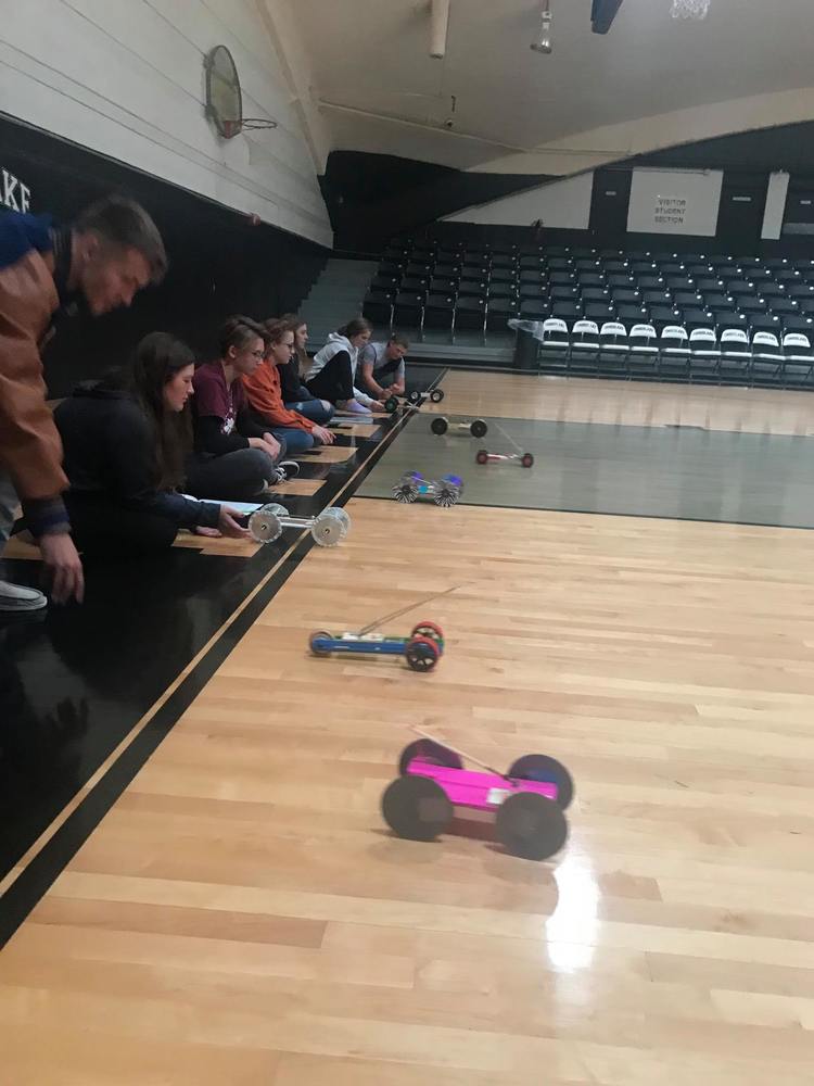 Small cars made from mouse traps are launched across a gym floor by students